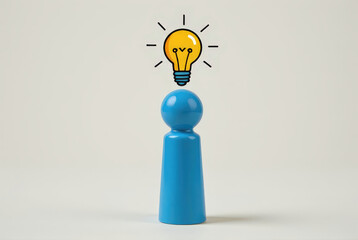 A blue peg doll, figure, with a light bulb above its head symbolizes creativity and ideas in a minimalistic setting.