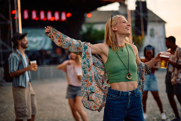 Carefree woman having fun and dancing while attending open air music festival in summer.