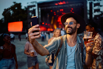 Happy man taking selfie while attending summer music festival in summer.