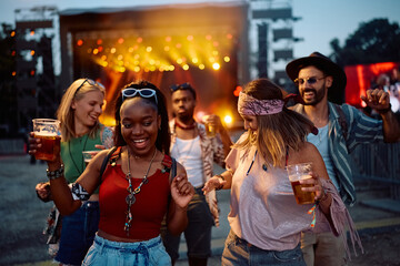 Cheerful friends dancing and having fun at summer music festival.