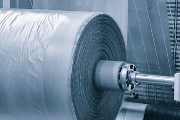 roll of plastic polyethylene film is cut by a food packaging machine. Industrial concept background