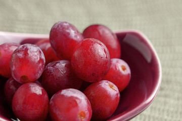 Red grapes close up in a ceramic bowl. Wet ripe berries