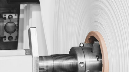 A machine with a roll of polyethylene plastic wrapping film on it. The machine is in a factory....