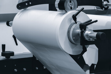 roll of plastic polyethylene film is cut by a food packaging machine. Industrial concept background. © Aleksandr Matveev