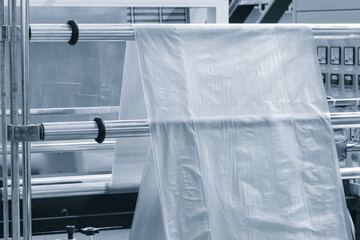 roll of plastic polyethylene film is cut by a food packaging machine. Industrial concept background.