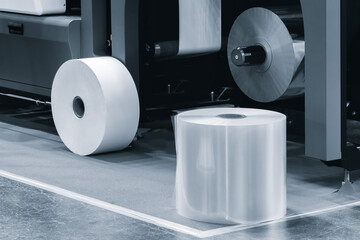 A machine with a roll of polyethylene plastic wrapping film on it. The machine is in a factory....