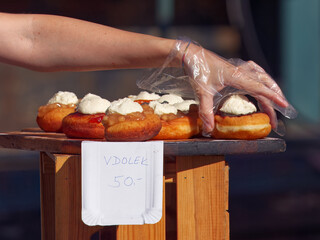 Close-up of a hand wearing a glove picking a delicious creamy dessert displayed at a rustic outdoor...