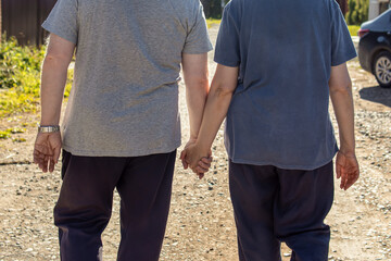 Man and a woman walking by the hand. View from the back