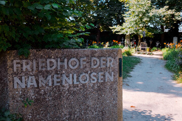 Vienna, Austria: Entrance to Friedhof der Namenlosen, the Cemetery of the Nameless. Stone sign in foreground, path leads to graves. Before Sunrise film location, peaceful setting.
