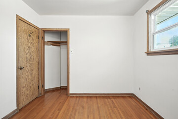 Small, empty room with a wooden door and a window