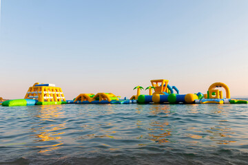 Water inflatable attraction on the seaside. Inflatable trampolines on an early summer morning, a colorful playroom on the water