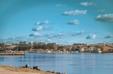 A couple sits by the Douro River on a tranquil afternoon, gazing across the serene water toward the...