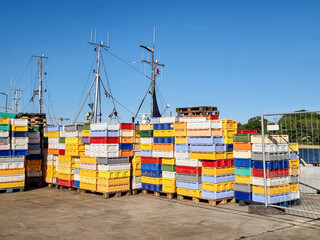 Colorful fish boxes stacked on pallets at a fishing harbor await the catch of the day