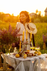 Decorated fancy table setting with candles, lemons in the purple lupins meadow. Beautiful woman...