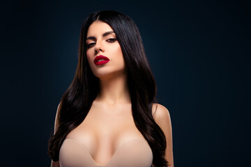 Portrait of a passionate brunette woman with red lipstick against a dark blue background, exuding...