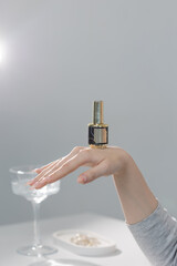 Elegant hand with beige manicure holding nail polish bottle, beauty salon close-up concept
