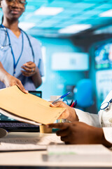 Young medical assistant gives the x ray results and patient file to physician, doing scan...