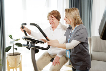 Senior woman doing exercise on bike simulator to keep her health and recovery after trauma