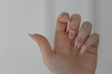 Elegant long almond nails with beige gel polish, close-up of stylish feminine hands