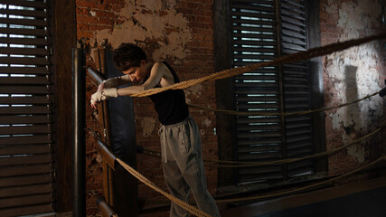 Boxer woman taking break on ropes, intense cinematic training session pause
