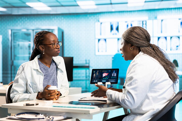 Woman physician meeting with patient for health care wellness consultation, evaluating medical...