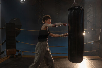 Boxing with a punching bag, sports achievements concept, female wrestler in a boxing ring, cinematic image, mood, motivating stories