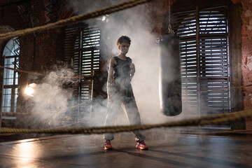 Stylish cinematic boxing shot, woman training with punching bag in dramatic gym lighting
