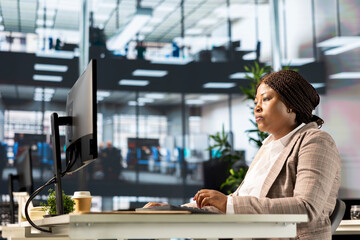 Black executive analyst finalizes a financial report and reviews data insights, developing a...