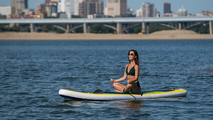 Caucasian woman doing yoga on a SUP board. 