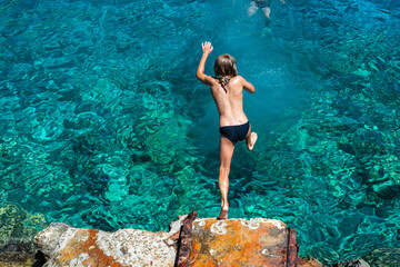 The thrill of summer captured as a young boy dives headfirst into the refreshing Ionian Sea at a...