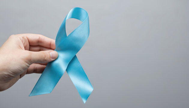 Light blue awareness ribbon held by hand against neutral background. Symbol represents support for sexual assault survivors, domestic violence prevention, awareness for conditions like prostate - Powered by Adobe