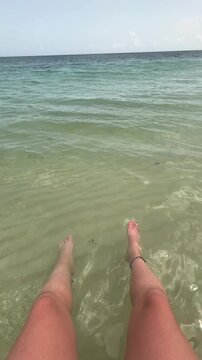 Traveler enjoying beautiful, calm Caribbean turquoise water feet in ocean water on the beach while on relaxing vacation