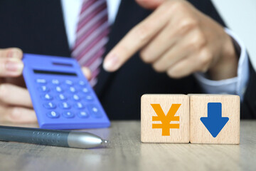 ビジネスマンと電卓。日本円記号と下向き矢印。