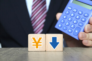 ビジネスマンと電卓。日本円記号と下向き矢印。