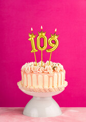 Pink birthday celebration cake with number 109 candle