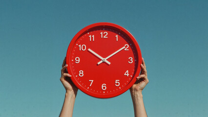 Bright red clock against blue sky