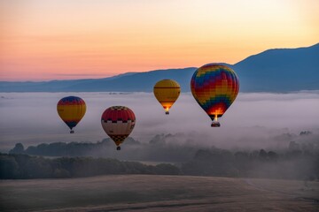 Fototapeta premium Photo of a group of hot air balloons float serenely over a misty landscape at sunrise, creating a breathtaking scene of adventure and tranquility
