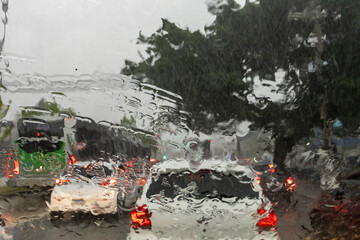 A car  is seen through a glass window with raindrops during a rainy day in São Paulo, Brazil.