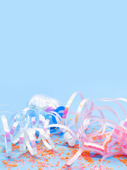 Colorful party streamers and confetti on a light blue background – festive flat lay ideal for...