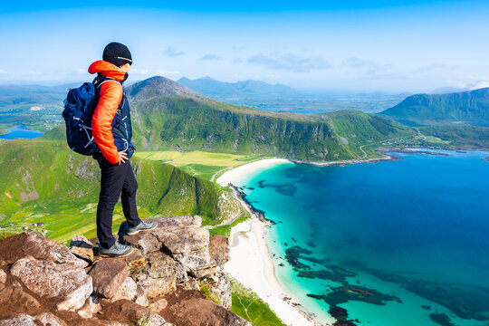 Female hiker enjoying spectacular view of Haukland beach with sea and mountains from Mannen peak, Lofoten Islands, Norway
