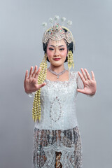 A graceful Indonesian bride in traditional Sundanese wedding attire extends both hands forward in a...