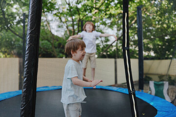 Happy children jumping on a trampoline in a sunny backyard, showcasing pure joy and playful energy...