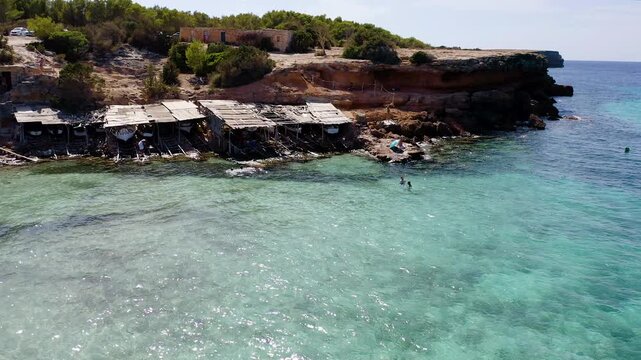 Aerial view of the small huts where the fishermen of Cala Saona keep their fishing boats, in Formentera, Spain.