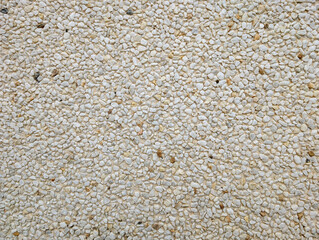Top view of exposed aggregate surface with gravel stone in off-white cream and ochre tones with light cement or concrete for wall, slab, tile, floor, interior, exterior. Cladding, natural texture. 