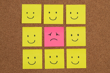 a group of sticky notes representing depression with a sad face surrounded with a lot of happy...