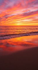 Obraz premium Vibrant sunset sky over blurred ocean waves meeting a dark sandy beach.