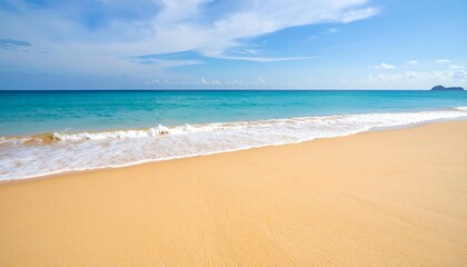 Fototapeta premium Golden beach meets turquoise sea under a partly cloudy sky