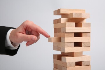 Lviv, Ukraine - December 04, 2023: Woman playing Jenga on light gray background, closeup