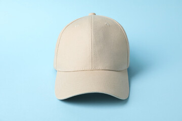 Beige baseball hat on light blue background, closeup. Mockup for design