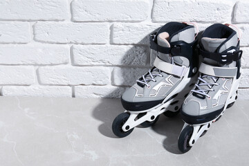 Pair of roller skates on grey marble table near white brick wall, above view. Space for text